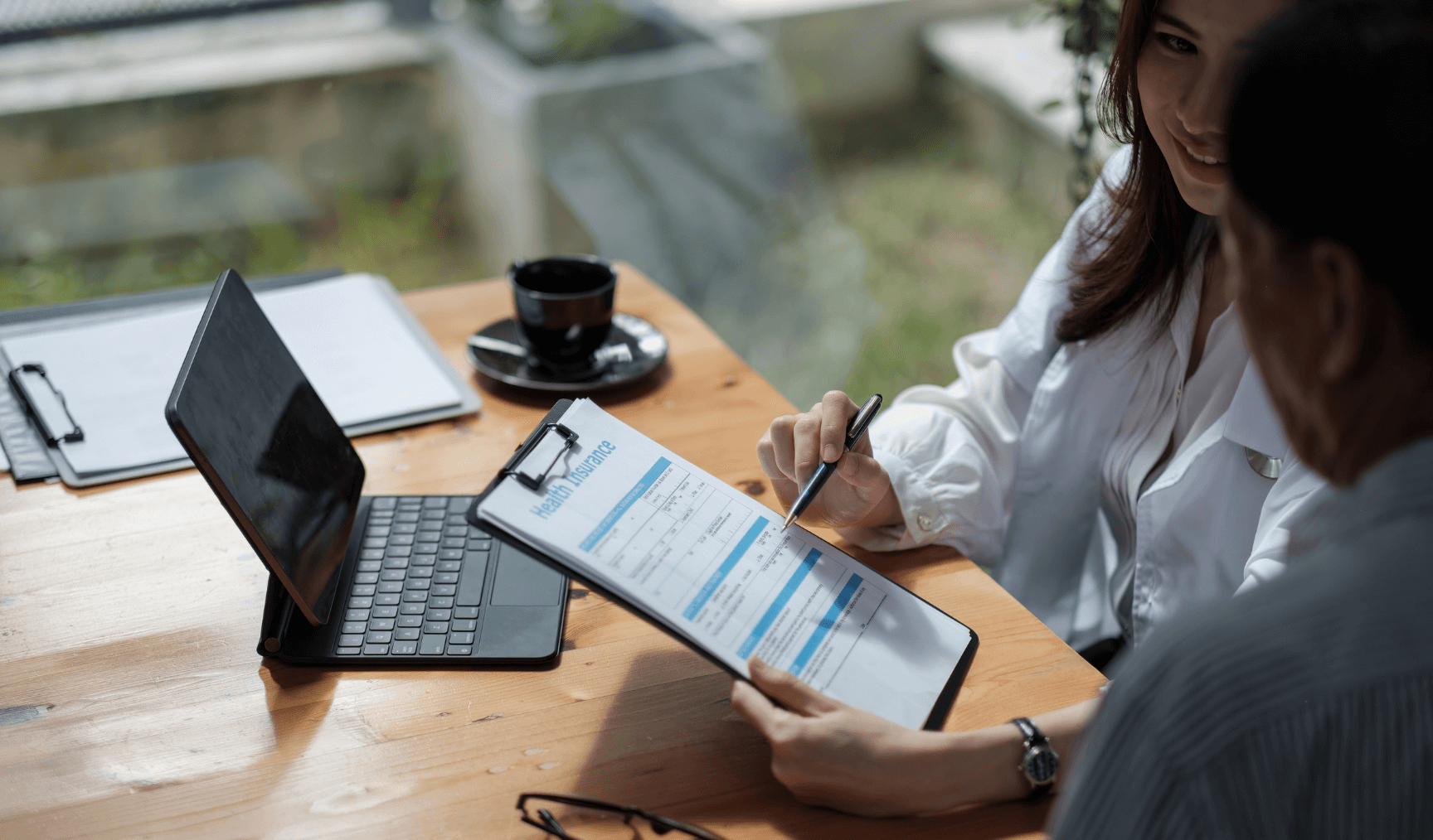 a man and woman discussing a health insurance form on a clipboard